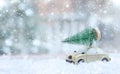 Retro toy car carrying tiny Christmas tree In Snowy Landscape. Fairytale, miniature scenery with snow and forest. Christmas cards Royalty Free Stock Photo