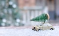 Retro toy car carrying tiny Christmas tree In Snowy Landscape. Fairytale, miniature scenery with snow and forest. Christmas cards Royalty Free Stock Photo