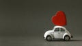 Retro toy car delivering wooden red heart at the roof for valentine`s day Royalty Free Stock Photo