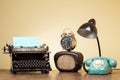 Retro typewriter, old radio, retro telephone, clock, desk lamp on wooden table. Vintage style photo