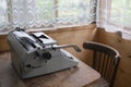 Retro typewriter stands on an old wooden table in a wooden house with large windows