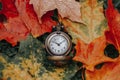 Retro vintage antique pocket watch clock lying on ground in autumn fall red yellow orange maple leaves Royalty Free Stock Photo