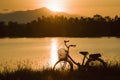 Retro vintage bicycle near the lake at sunset moment. silhouette bicycle at the sunset with grass field.big mountain and sunset Royalty Free Stock Photo