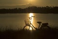 Retro vintage bicycle near the lake at sunset moment. silhouette bicycle at the sunset with grass field.big mountain and sunset