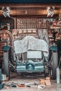 Retro vintage car covered by white cloth. Renovation project in the garage with lots of mechanical details and tools Royalty Free Stock Photo