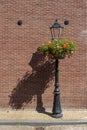 Retro vintage lamp and lantern is made of cast iron. Historical illumination on the street during sunny daylight, brick wall in Royalty Free Stock Photo