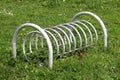 Retro vintage partially rusted grey metal bicycle stand surrounded with uncut grass in local public park