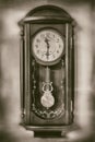 Vintage old wall clock on the white wall on background in sepia style