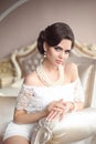 Retro woman brunette beauty portrait. Elegant lady with hairstyle and makeup, pearl jewelry set posing on modern armchair in lux Royalty Free Stock Photo