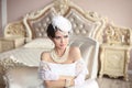 Retro woman portrait. Elegant brunette lady in hat with hairstyle, pearls jewelry set. Pretty female posing on modern armchair in Royalty Free Stock Photo