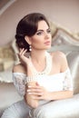 Retro woman portrait. Elegant brunette lady with wavy hairstyle, pearls jewelry set. Pretty female posing on modern armchair in l Royalty Free Stock Photo