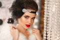 Retro woman in white fur coat. Cristmas portrait. Elegant lady with feather in wedding hairstyle, beauty makeup and diamond black Royalty Free Stock Photo