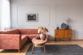 Wooden cabinet with black vases in the corner of classy grey living room interior with ginger sofa Royalty Free Stock Photo