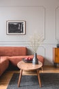 Wooden cabinet with black vases in the corner of classy grey living room interior with ginger sofa Royalty Free Stock Photo