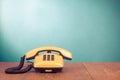 Retro yellow telephone on oak wooden table front mint blue background Royalty Free Stock Photo