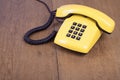 Retro yellow telephone on old textured wooden table background