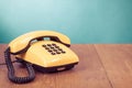 Retro yellow telephone on wooden table near aquamarine wall background