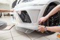 Retrofitting the car with a solid transparent protective film, the master smooths the surface by squeezing air bubbles with a Royalty Free Stock Photo