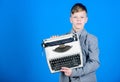 Retrospective study. Boy hold retro typewriter on blue background. What to do with this thing. Out of date. I need Royalty Free Stock Photo