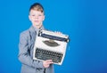 Retrospective study. Boy hold retro typewriter on blue background. What to do with this thing. Out of date. I need Royalty Free Stock Photo