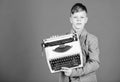 Retrospective study. Boy hold retro typewriter on blue background. What to do with this thing. Out of date. I need Royalty Free Stock Photo