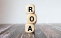 Return on Asset. ROA the word on wooden cubes, cubes stand on a reflective surface Royalty Free Stock Photo