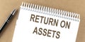 RETURN ON ASSETS text on a notepad with pen, business concept Royalty Free Stock Photo