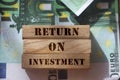 Return on Investment words on wooden blocks on banknotes of 100 Euro value. ROI business analysis concept Royalty Free Stock Photo