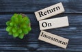 RETURN, ON, INVESTMENT, words on wooden blocks on a beautiful dark background with cactus Royalty Free Stock Photo