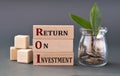 Return on Investment - words on wooden blocks with a jar of coins on a gray background Royalty Free Stock Photo