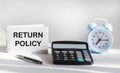 RETURN POLICY text written on notepad, next to calculator, clock and pen on white background Royalty Free Stock Photo