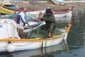 Returning from fishing, the fisherman is picking fish from the nets in the boat.