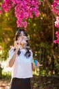 Portrait of Young woman blowing soap bubbles on pink flowers background on the beach. Royalty Free Stock Photo