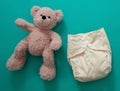 Reusable cloth baby diaper. Eco friendly nappy and teddy bear on green background