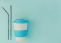 Reusable eco cup and metal drinking straws on blue background. Top view, copy space. Royalty Free Stock Photo