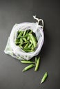 Reusable eco-friendly bag full of fresh seasonal pea pods on black background Royalty Free Stock Photo