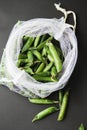 Reusable eco-friendly bag full of fresh seasonal pea pods on black background Royalty Free Stock Photo