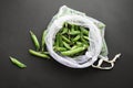 Reusable eco-friendly bag full of fresh seasonal pea pods on black background Royalty Free Stock Photo