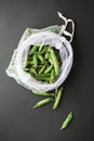 Reusable eco-friendly bag full of fresh seasonal pea pods on black background Royalty Free Stock Photo