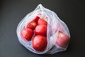 Reusable eco-friendly bag full of fresh seasonal tomatoes on black background