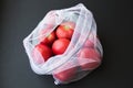 Reusable eco-friendly bag full of fresh seasonal tomatoes on black background