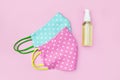 Reusable homemade fabric mask for the face and a sanitizer spray bottle. pink background