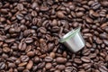 Reusable metal coffee capsule on the dark roasted coffee bean Royalty Free Stock Photo