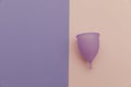 Reusable pastel purple menstrual cup on a colorful background. Women's hygiene, menstruation, critical days