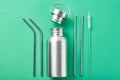 Reusable plastic free items on a green background. Top view of aluminun bottle and metal tubes. Zero waste eco friendly concept