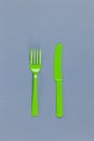 Reusable recyclable green fork, knife made from corn starch on grey background. Eco, zero waste, alternative to plastic concept.