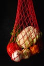 Reusable red net bag with fresh vegetables on a black background. Zero waste, recycling, plastic free lifestyle concept Royalty Free Stock Photo