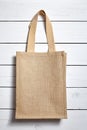 Reusable shopping bag, natural textile fiber, eco hessian or jute sack on white wooden background Royalty Free Stock Photo