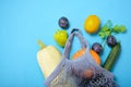 Reusable shopping String bag, open netted bag with fresh apples. blue Mesh shopping bag with fruits on green shadow background.