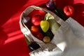 Reusable shopping textile bag full of groceries, fresh fruits and vegetables purchased from the store on red background Royalty Free Stock Photo